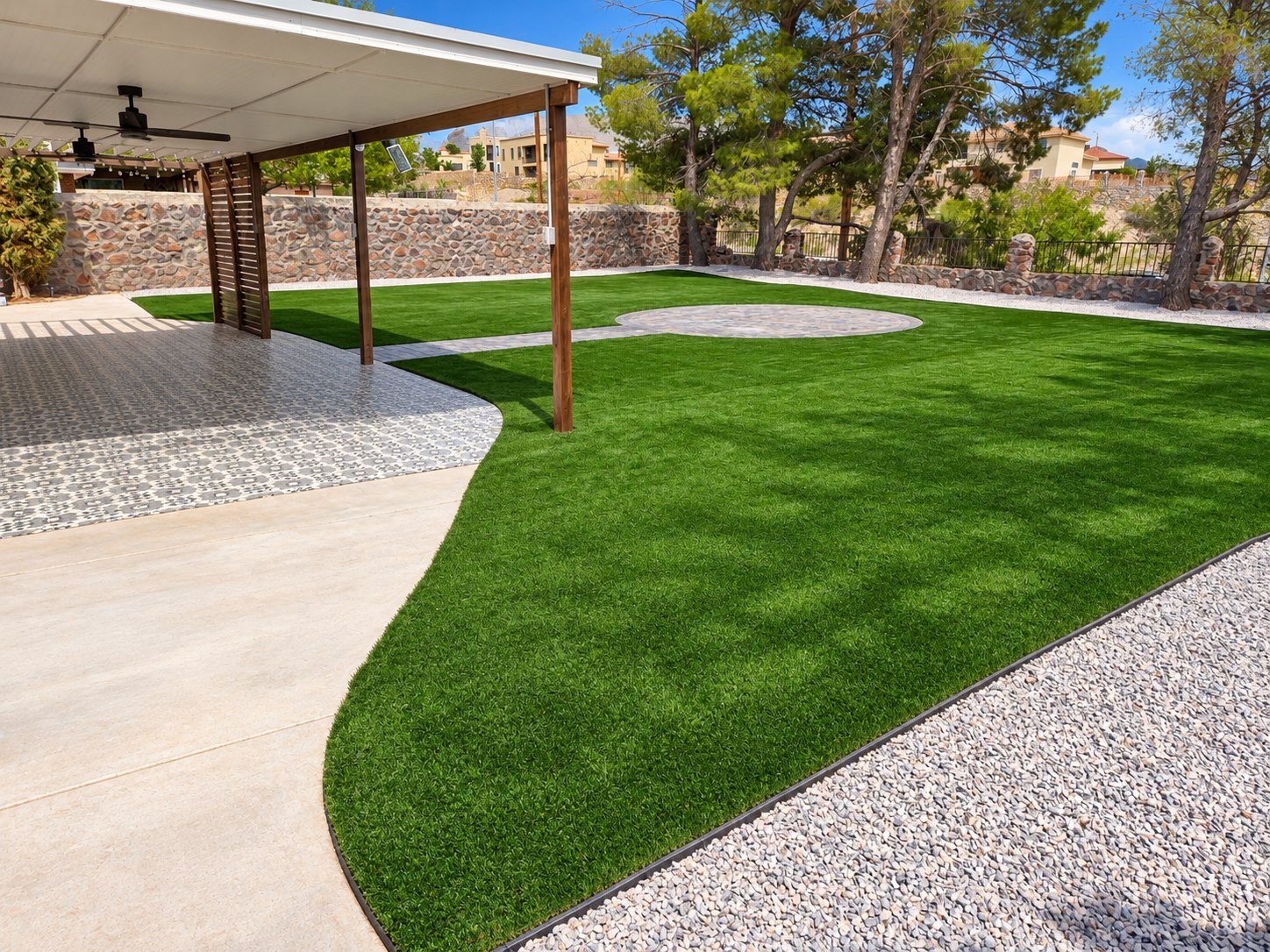Backyard with green turf, a circular paved gathering area and a covered patio